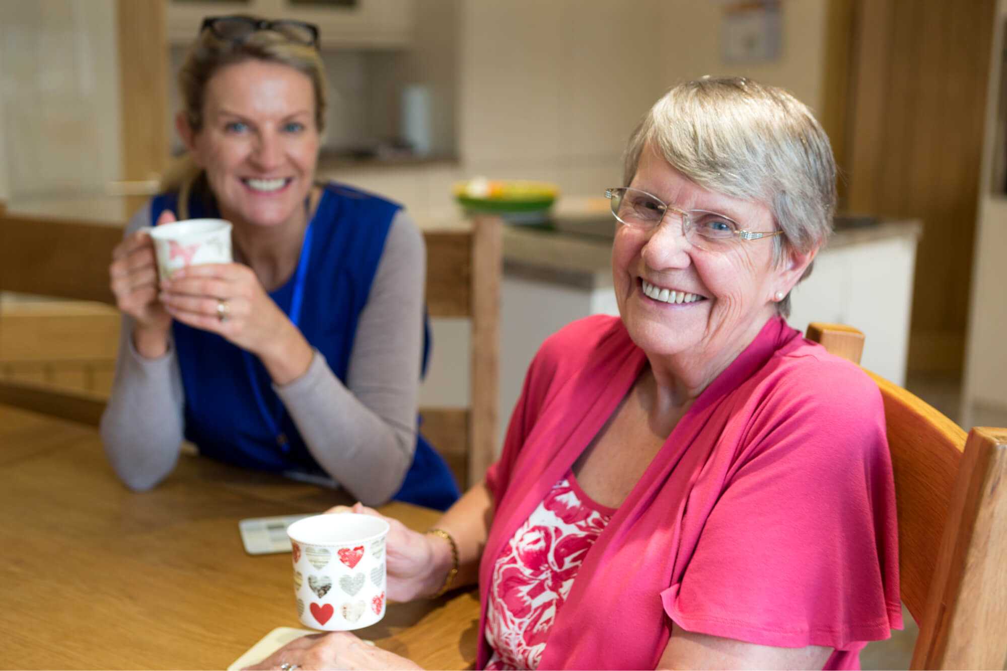 Elderly resident having tea with carer